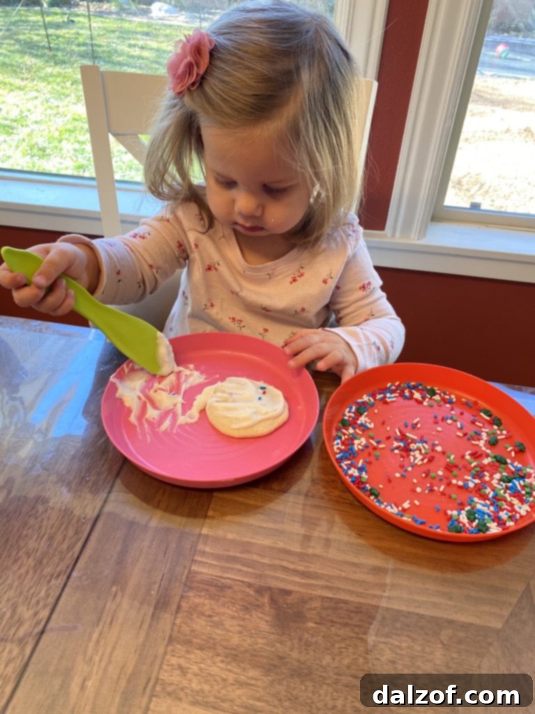 Chewy Applesauce Oat Chocolate Chip Delights 10 A young child enjoying a freshly baked and frosted sugar cookie, covered in colorful sprinkles.