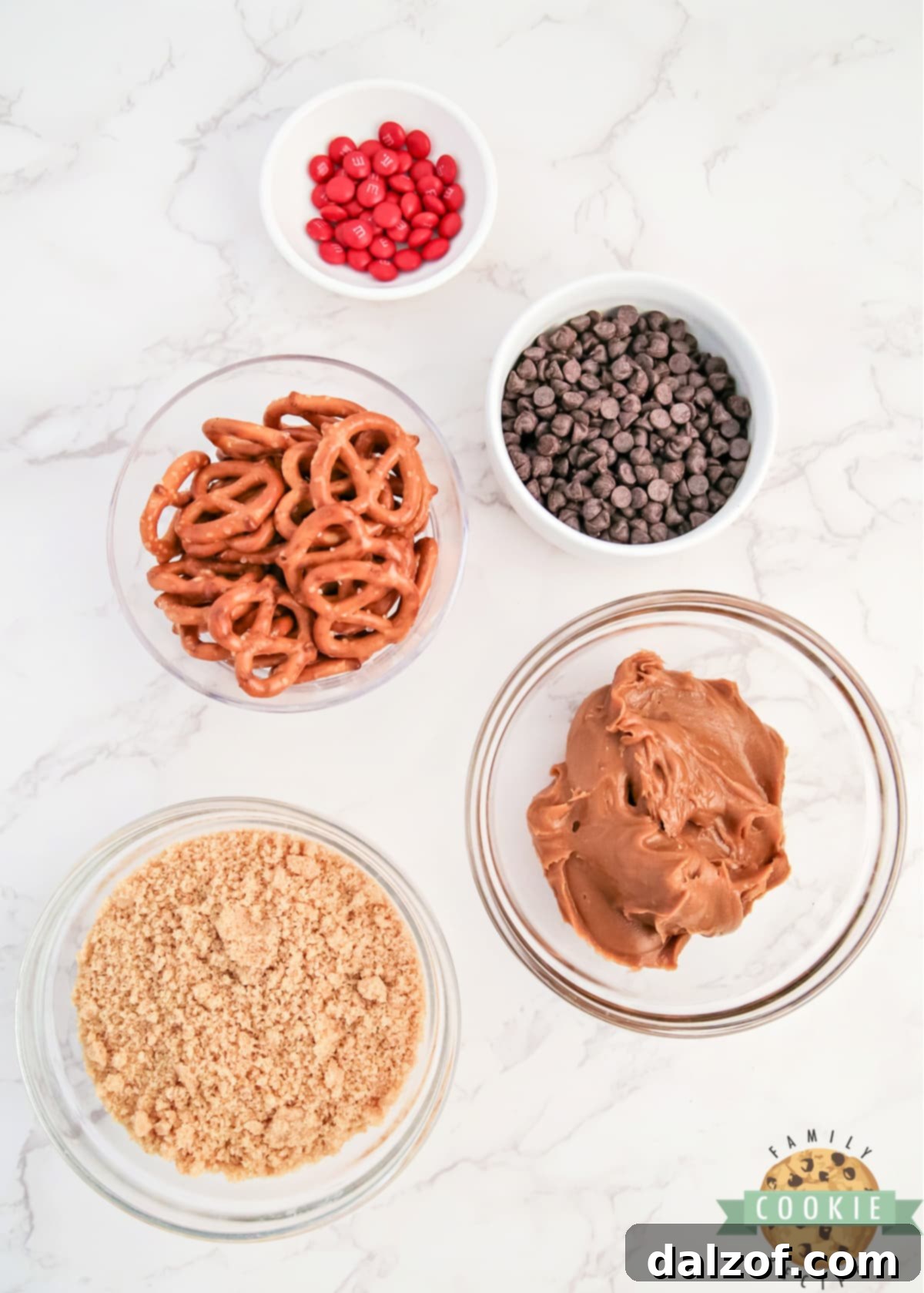 Rudolph's Red-Nosed Cookie Butter Delights 4 Essential ingredients for Rudolph Cookie Butter Balls: cookie butter, crushed Nilla wafers, mini pretzels, chocolate chips, and M&Ms.