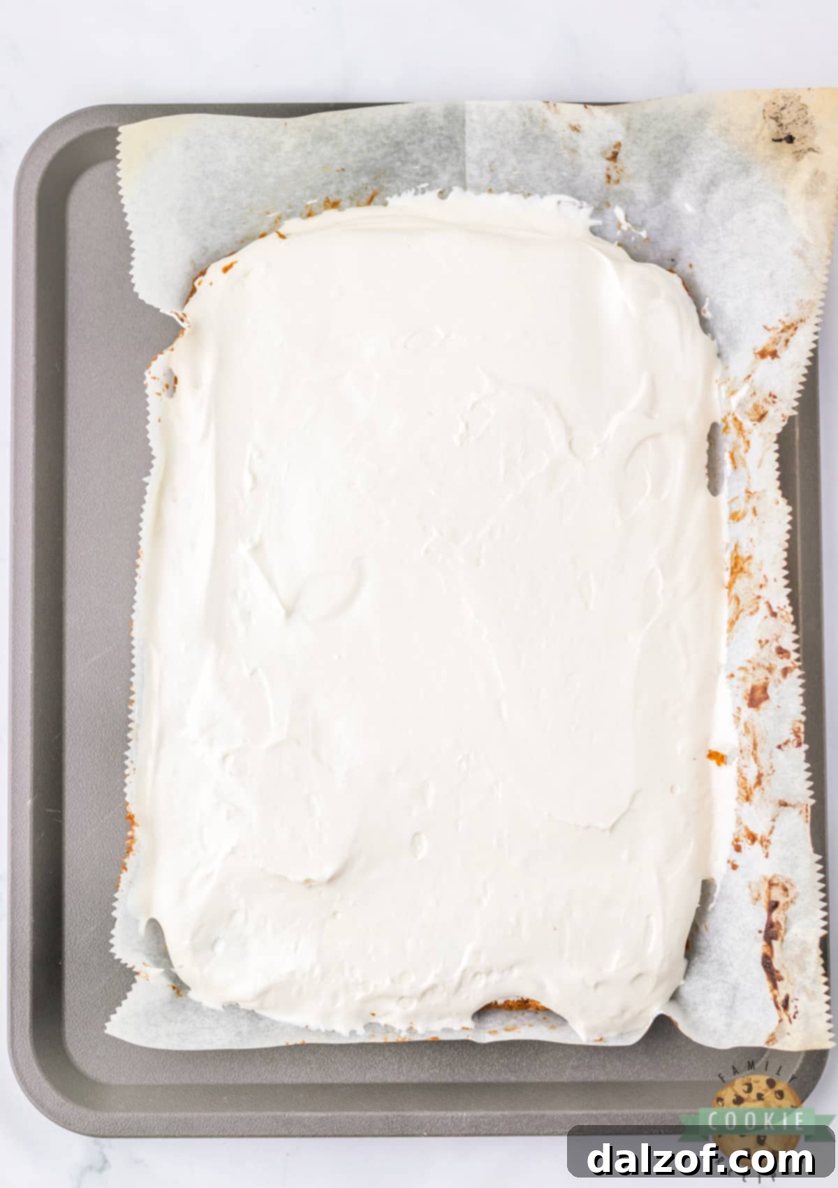 Carefully spreading the fluffy marshmallow filling over one cooled oatmeal cookie layer.