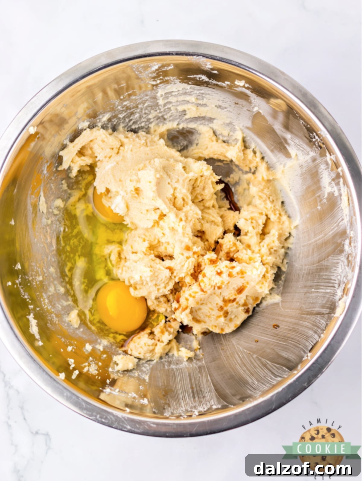 Adding eggs and vanilla extract to the creamed butter and sugar mixture for the cookie dough.