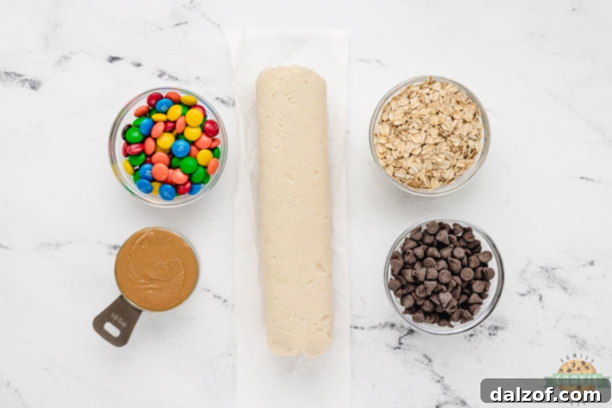 Key ingredients for 5-Ingredient Monster Cookies laid out: sugar cookie dough, peanut butter, chocolate chips, M&Ms, and old-fashioned oats.