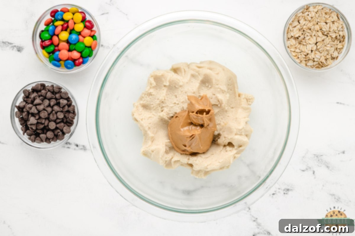 Mixing peanut butter into softened sugar cookie dough in a large bowl, the first step for 5-Ingredient Monster Cookies.