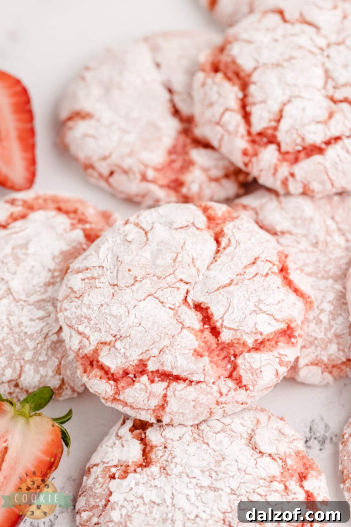 Close-up shot of several strawberry cookies, some coated in powdered sugar, highlighting their crinkled tops and soft appearance.