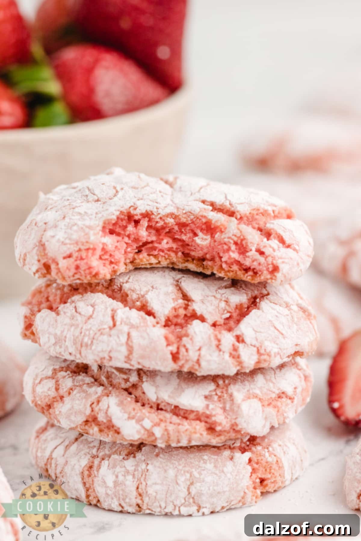 An overhead shot of several strawberry cake mix cookies dusted with powdered sugar, arranged on a white surface.