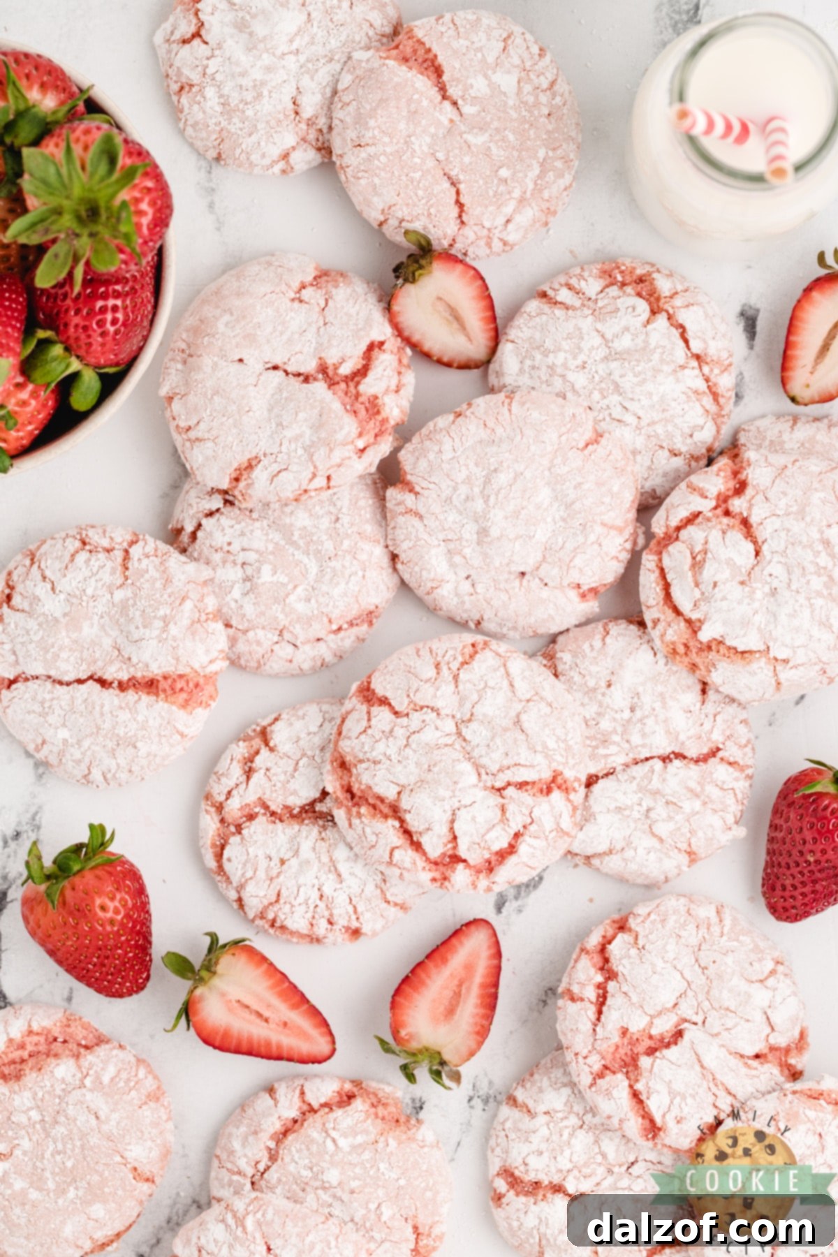 A close-up of a single Strawberry Cool Whip Cookie, perfectly round and coated in powdered sugar, ready to be eaten.