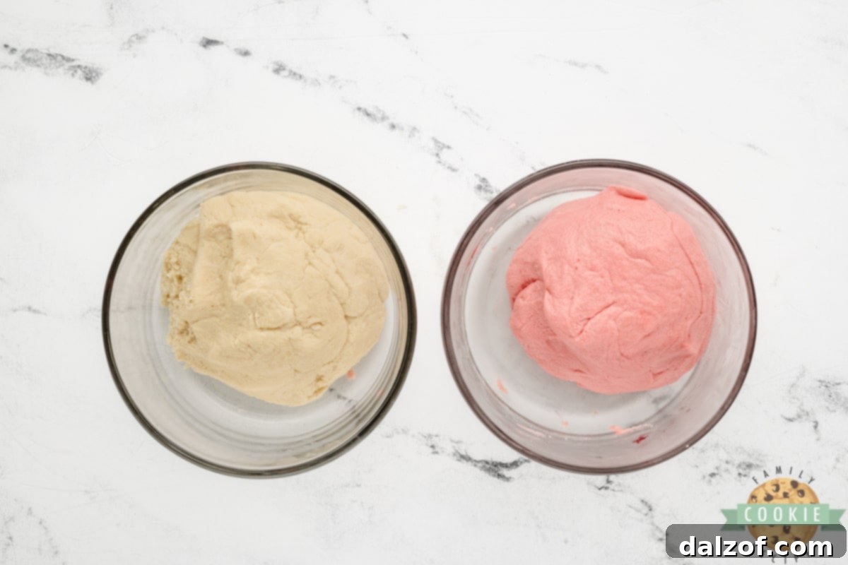 Sugar cookie dough divided into two portions, one left white and the other dyed pink with food coloring.