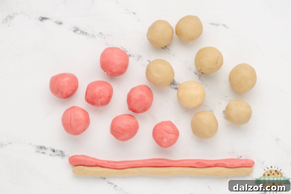 Small balls of pink and white cookie dough rolled into uniform 8-inch ropes, ready for twisting.