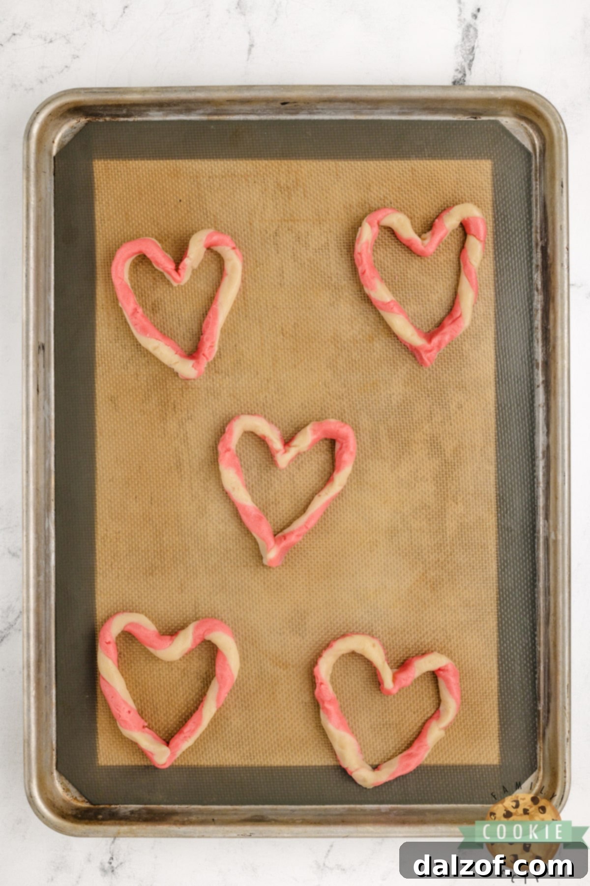 Pink and white twisted cookie dough shaped into a perfect heart, ready for baking.