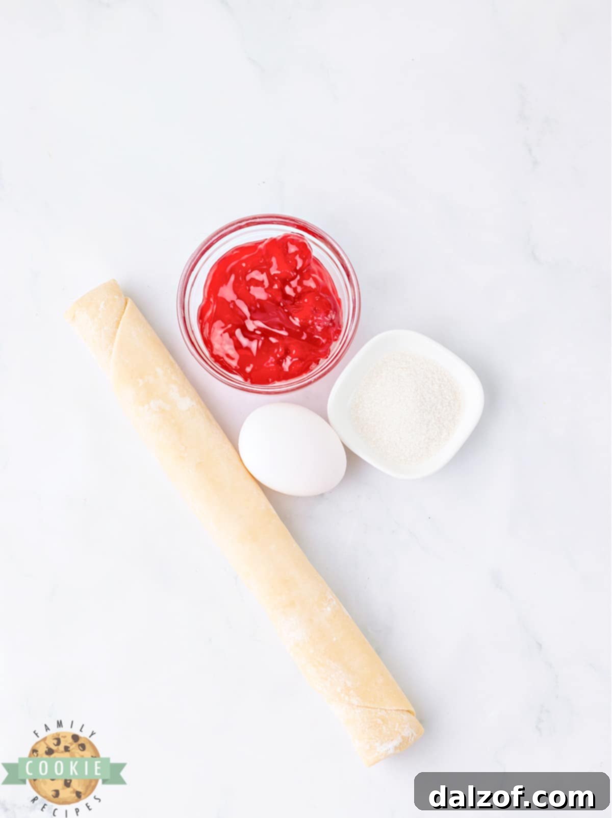 Key ingredients for making delightful Strawberry Pie Cookies, showcasing pie crusts, strawberry pie filling, an egg, and sanding sugar.