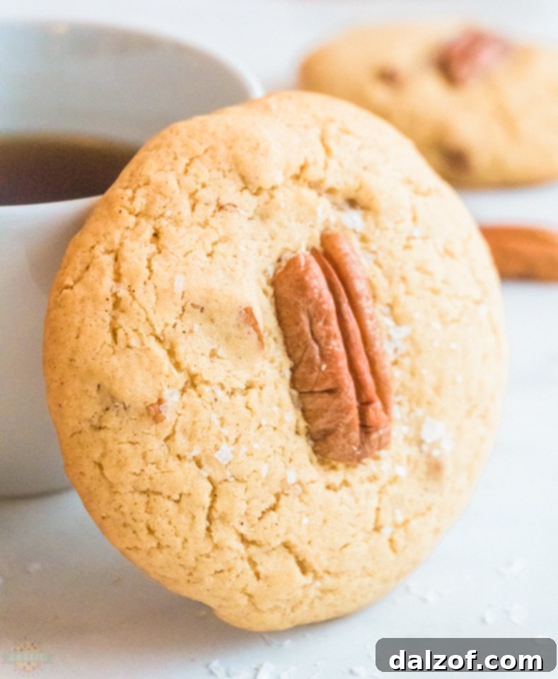Close-up of freshly baked Butter Pecan Cookies with whole pecans on top, showcasing their soft texture and golden-brown edges