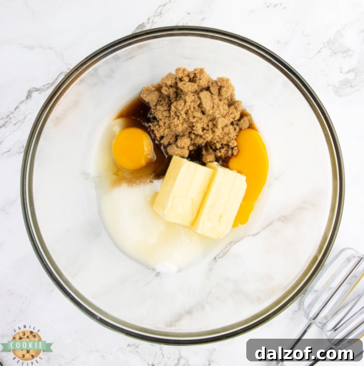 A bowl containing butter, sugars, and eggs being creamed together, forming a smooth, light mixture.
