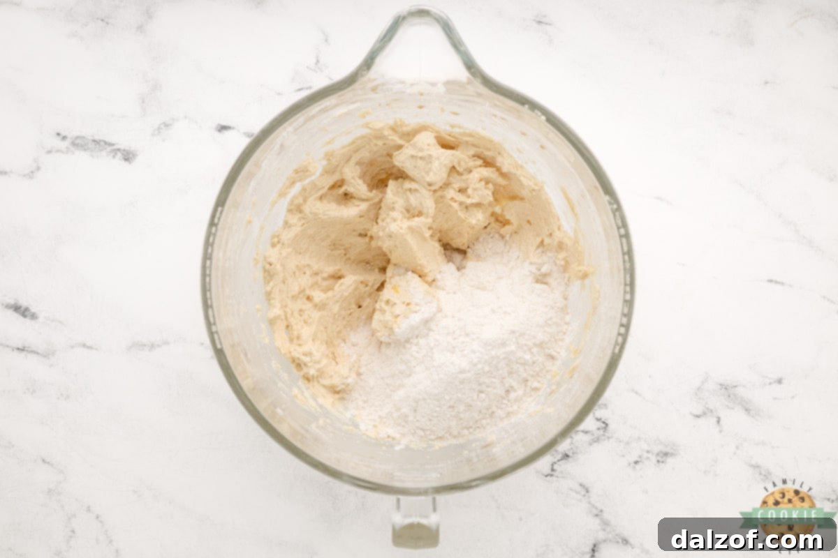 Sifting all-purpose flour and salt into the wet ingredients for Snickerdoodle Cookie Bars, preparing to mix until just combined.