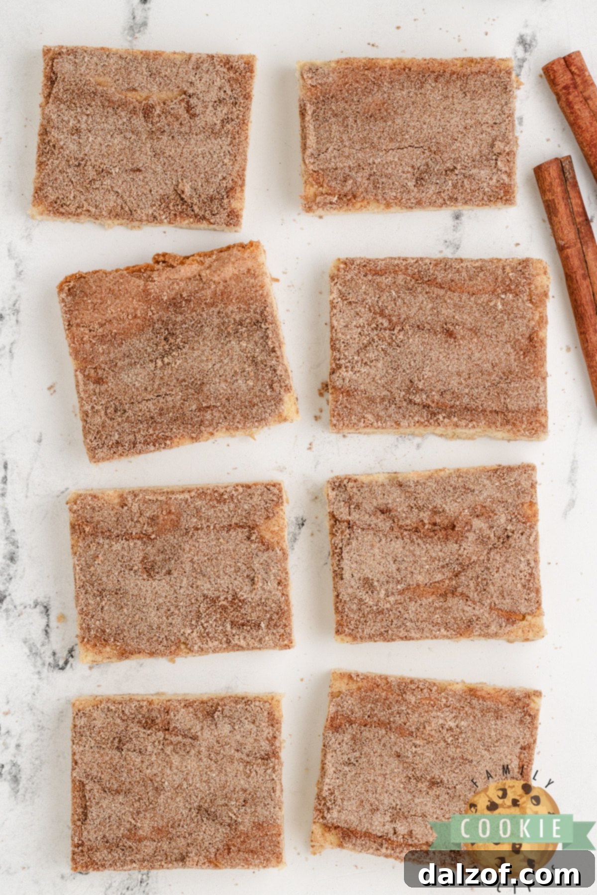 Close-up of unbaked Snickerdoodle Cookie Bars dough evenly spread in a baking pan, generously coated with a cinnamon and sugar topping, ready for the oven.