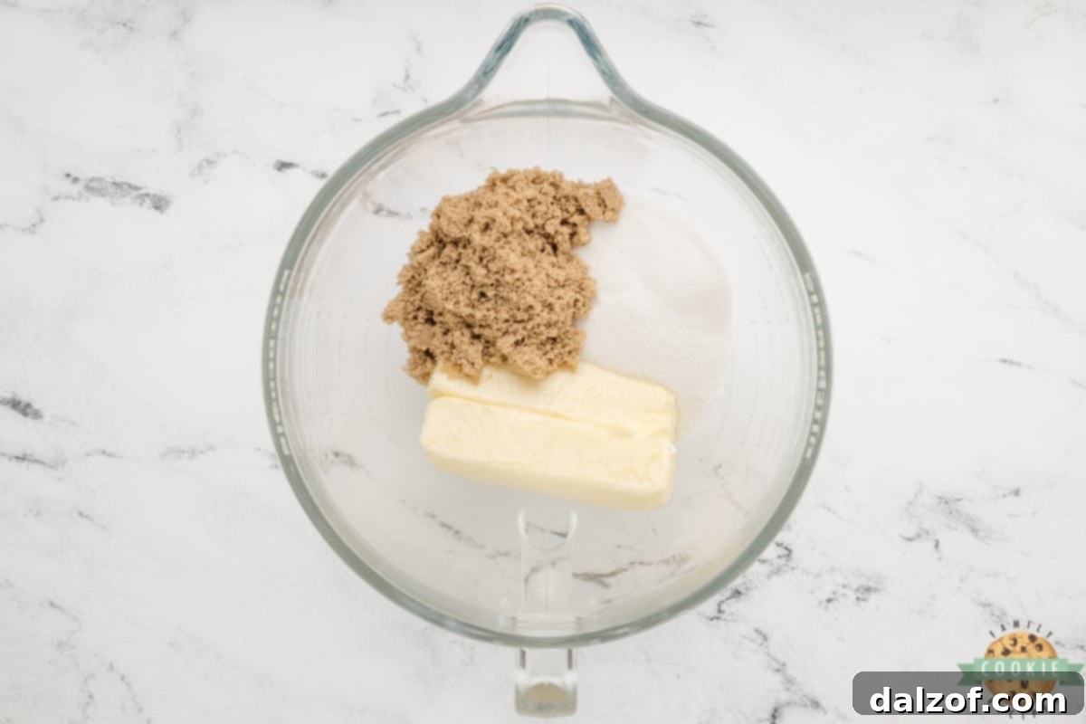 Creaming together softened butter and granulated and brown sugars in a mixing bowl until light and fluffy.