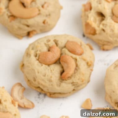 A close-up of a stack of golden brown cashew cookies, showing their texture and deliciousness.