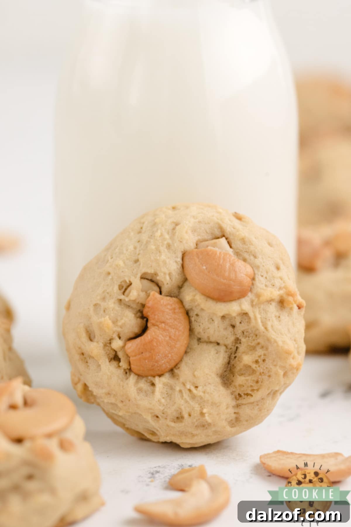 A single Cashew Cookie paired with a glass of milk, emphasizing its perfect shape and inviting texture.