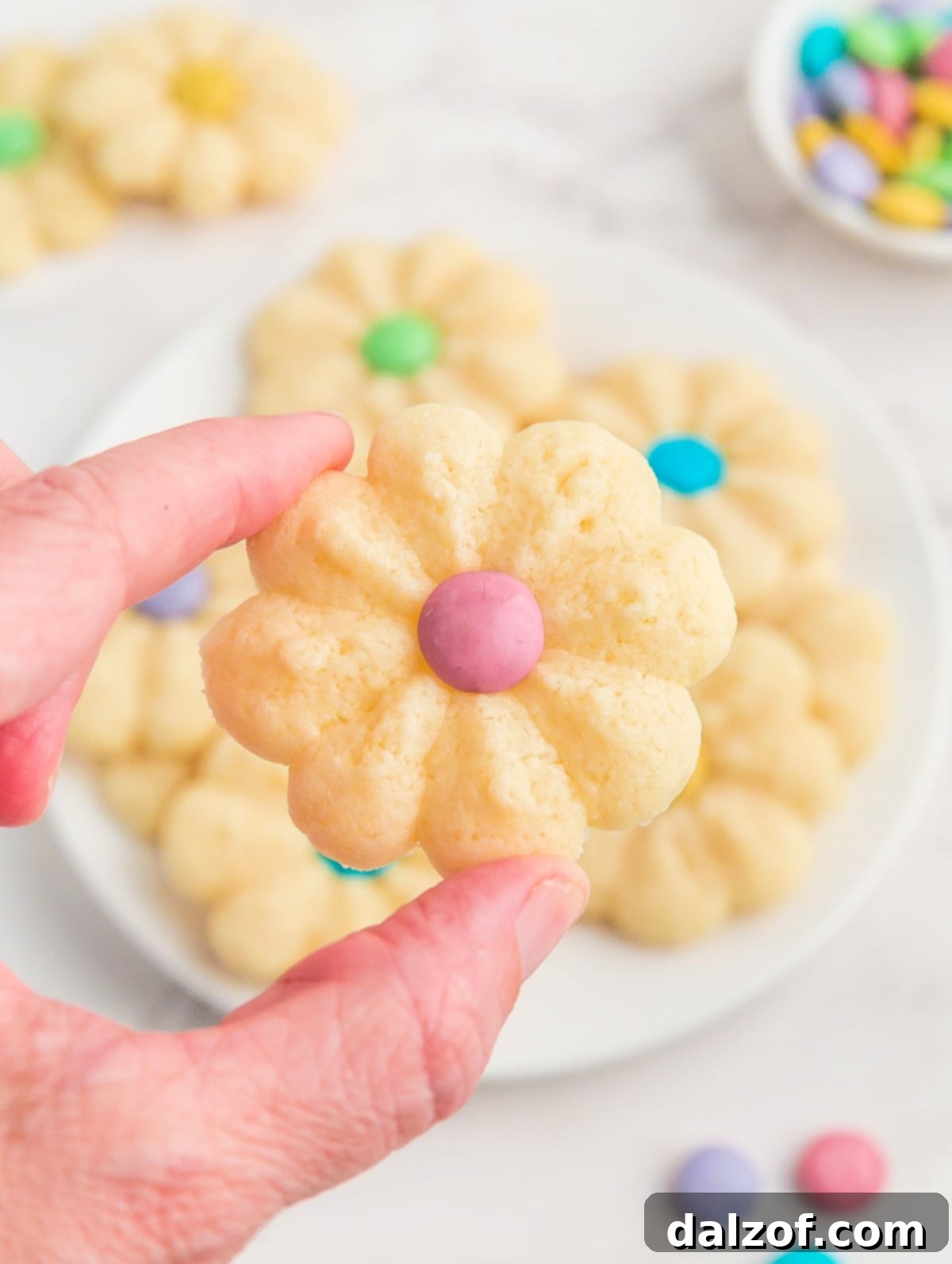 A perfectly baked flower cookie, exquisitely decorated with a vibrant M&M center, ready to be enjoyed.