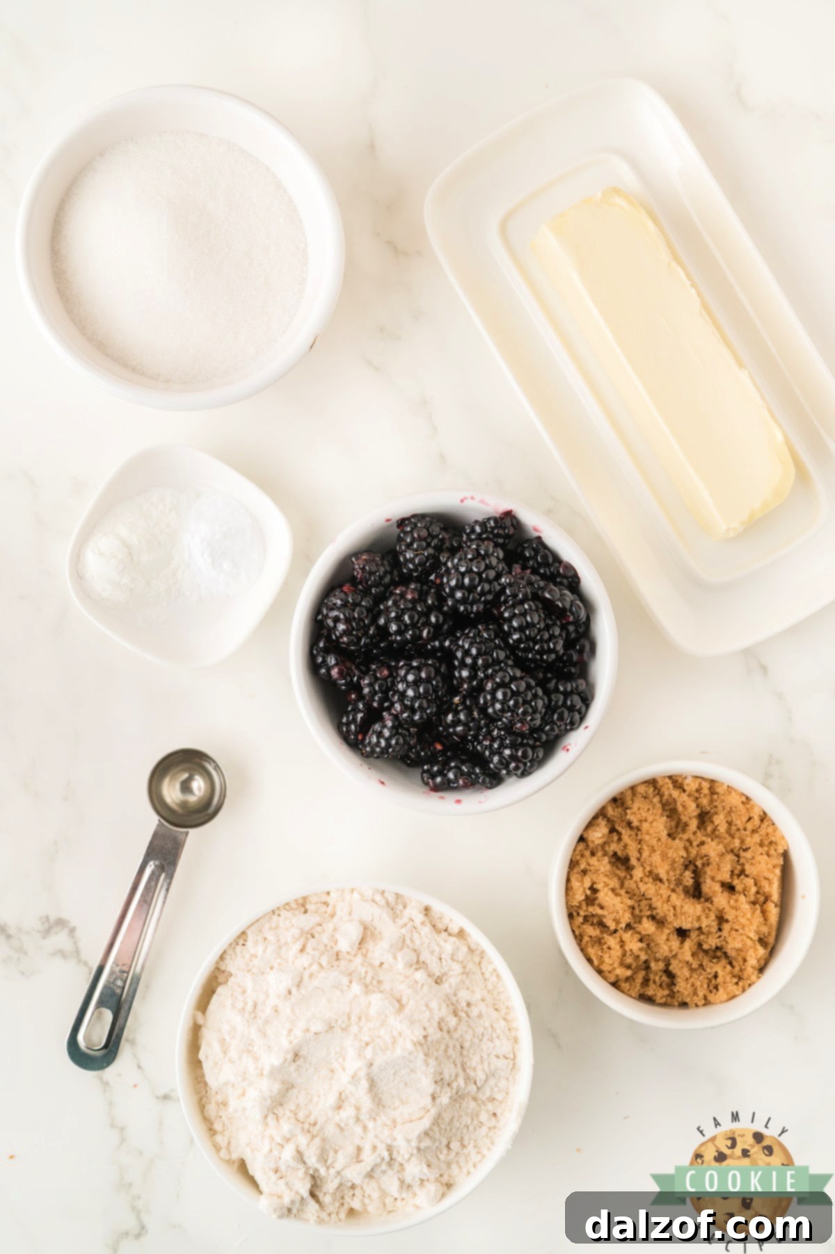 A flat lay of fresh ingredients laid out for baking Blackberry Cookies, including softened butter, sugars, lemon extract, flour, baking powder, baking soda, and vibrant blackberries.