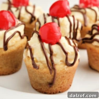 Finished Banana Split Cookie Cups with creamy pineapple filling, chocolate drizzle, and a cherry topping.