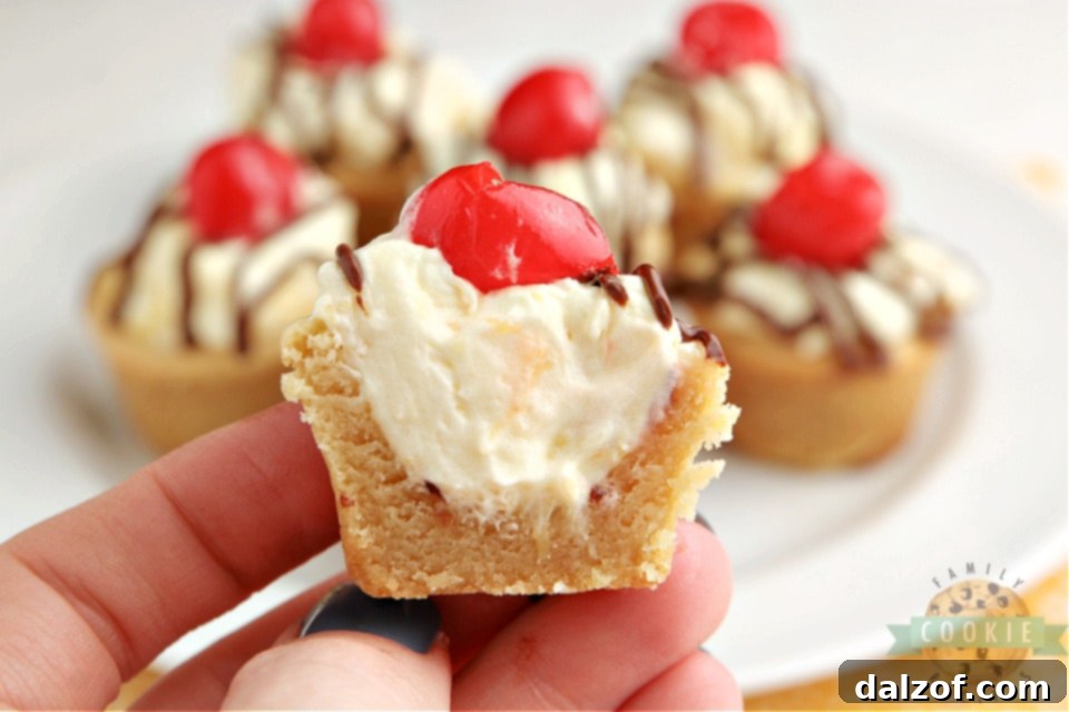 Close-up of a single Banana Split Cookie Cup, showcasing the creamy pineapple filling, rich chocolate drizzle, and a bright red cherry, ready to be enjoyed.