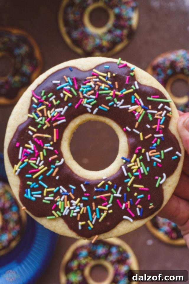 Close-up of a stack of chocolate glazed donut cookies with colorful sprinkles.