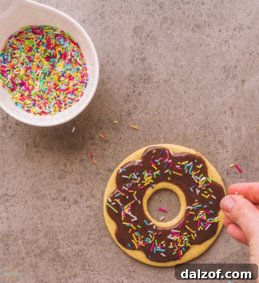 Freshly cut donut cookie shapes arranged on a baking sheet lined with parchment paper.