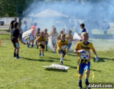 Boys running through a flag football entrance tunnel with smoke