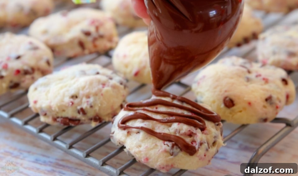 A batch of Chocolate Raspberry Cheesecake Cookies being drizzled with melted chocolate.