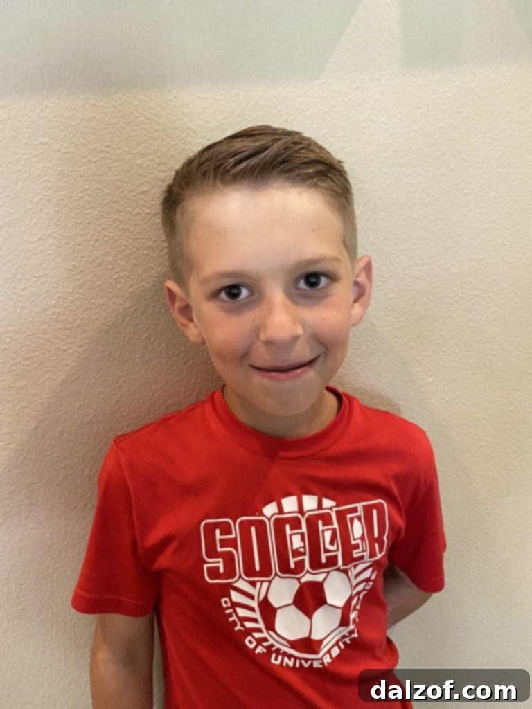 A young boy with a fresh haircut, smiling warmly for the camera