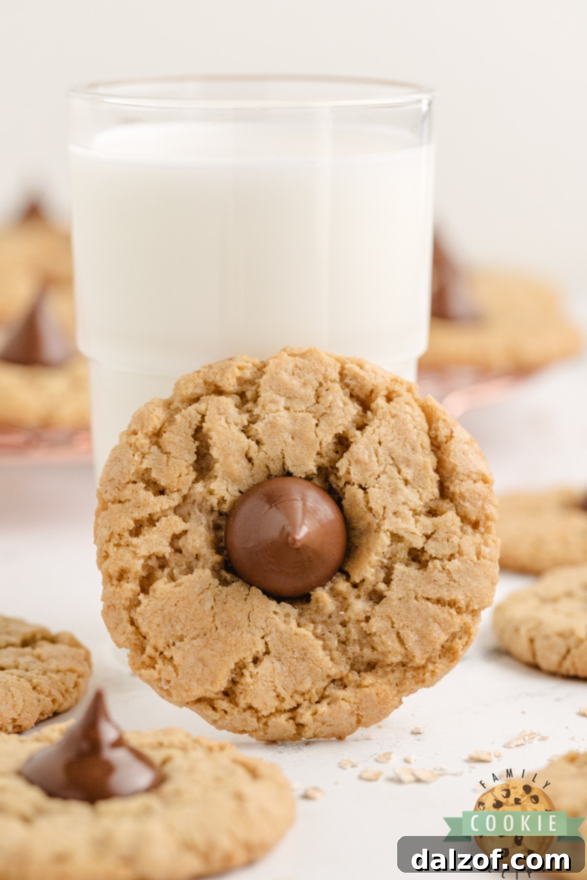 A glass of cold milk paired with a freshly baked Oatmeal Kiss Cookie, showcasing the soft texture and inviting chocolate topping. The perfect treat any time.