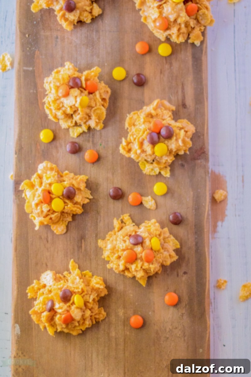 A stack of golden no-bake cornflake cookies with Reese's Pieces on a white plate