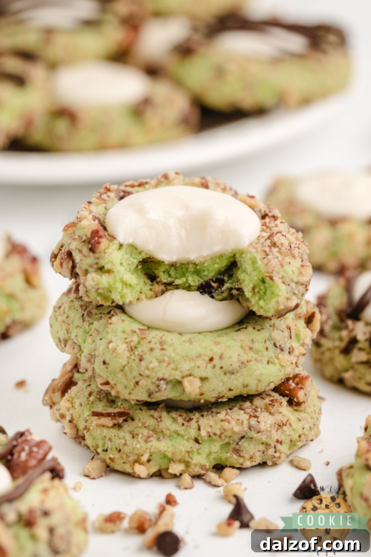Stack of pistachio thumbprint cookies made with buttercream filling.