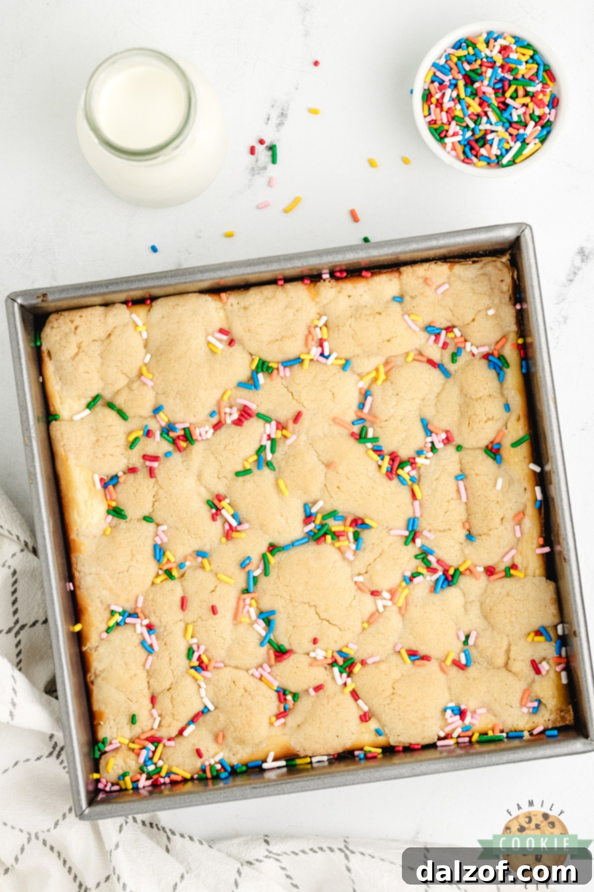 Sugar cookie bars with sprinkles and cheesecake filling, cut into squares.