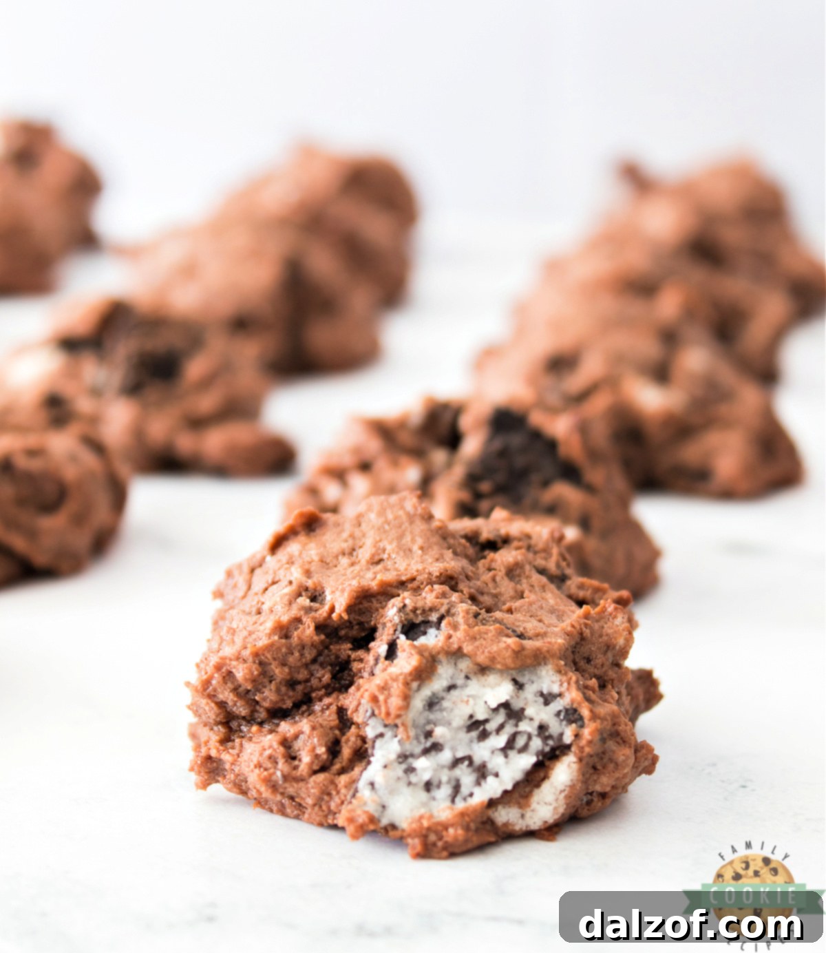 A single Chocolate Oreo Cheesecake Cookie with a bite taken out, showing the soft interior and Oreo pieces.