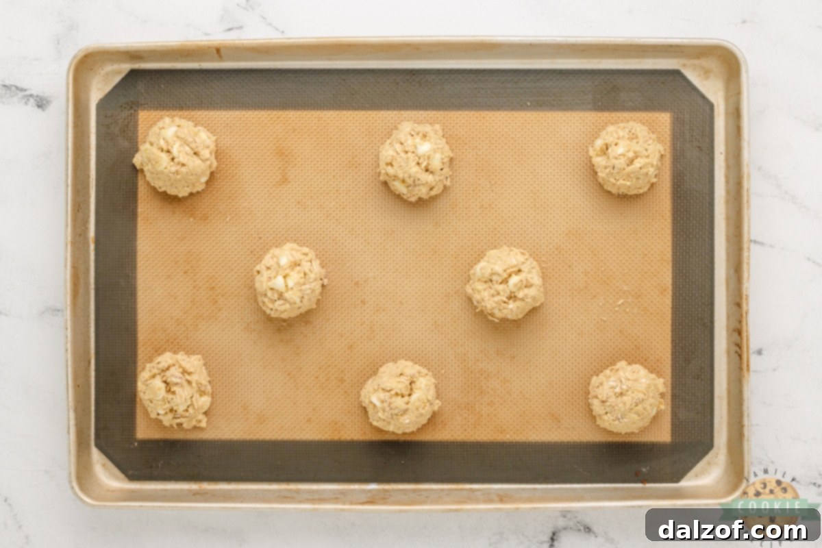 Rounded teaspoonfuls of cookie dough placed on a parchment-lined baking sheet.