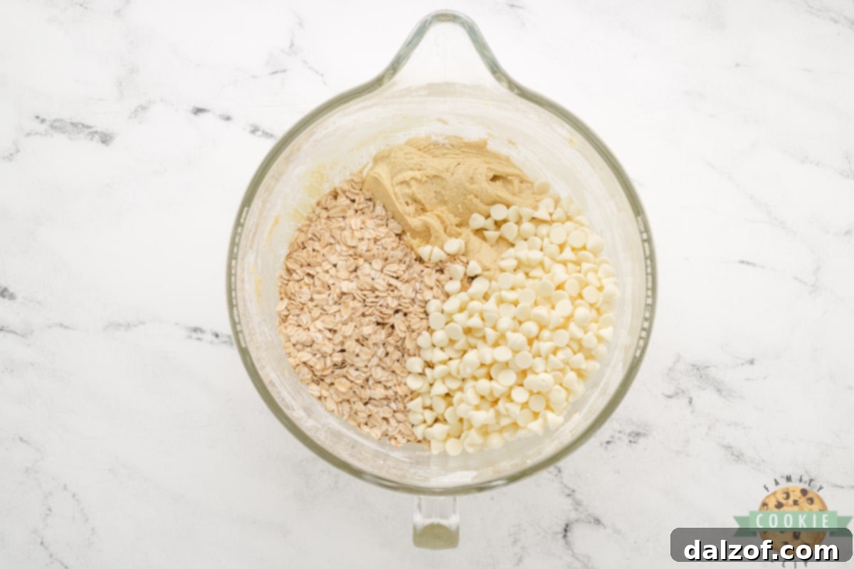 Gently folding in white chocolate chips and rolled oats into the lemon cookie dough.
