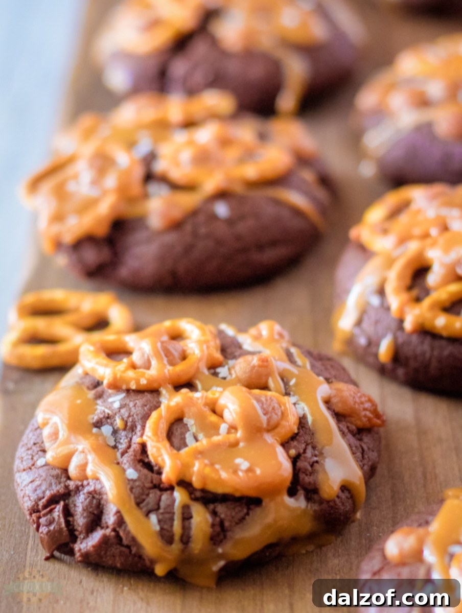 Close-up of a stack of Salted Caramel Brownie Cookies with melted caramel and pretzel pieces