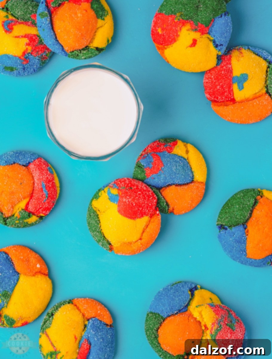 Ingredients for vibrant colorful cake mix cookies laid out on a clean kitchen counter: white cake mix, vegetable oil, eggs, various food colorings, and granulated sugar.