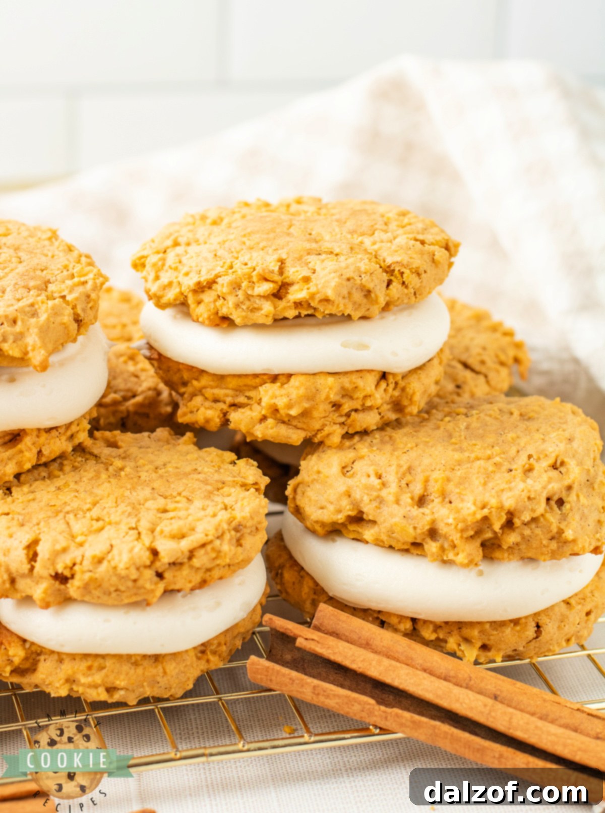 Stack of pumpkin oatmeal sandwich cookies filled with cream cheese frosting.