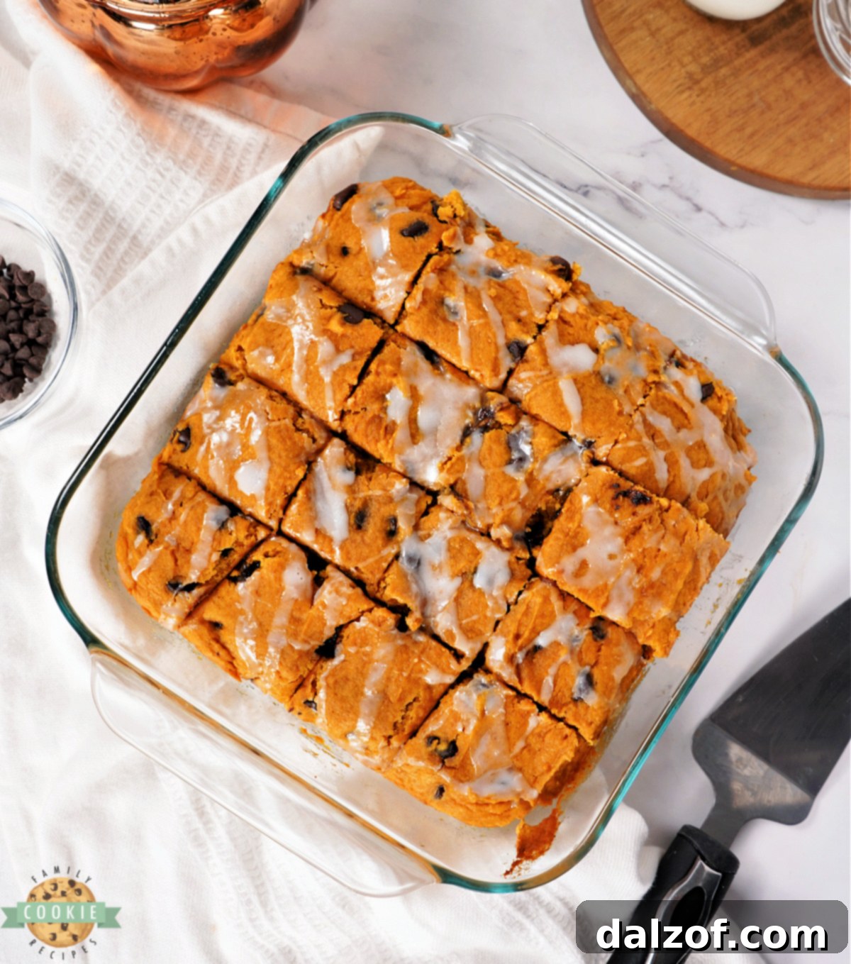 Square pan of pumpkin bars drizzled with glaze, ready to be served, capturing the essence of an easy fall dessert.