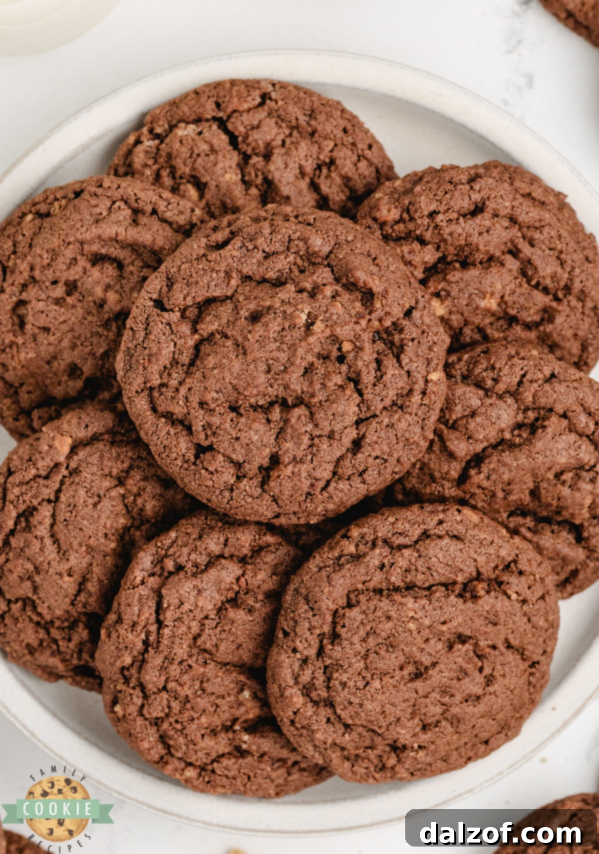 A hand reaching for a Chocolate Graham Cracker Cookie from a tray of freshly baked goods.
