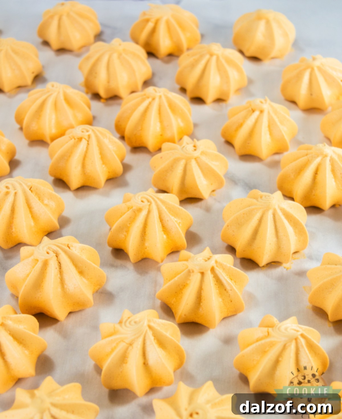 Tray of bright orange Pumpkin Meringues cooling on parchment paper.