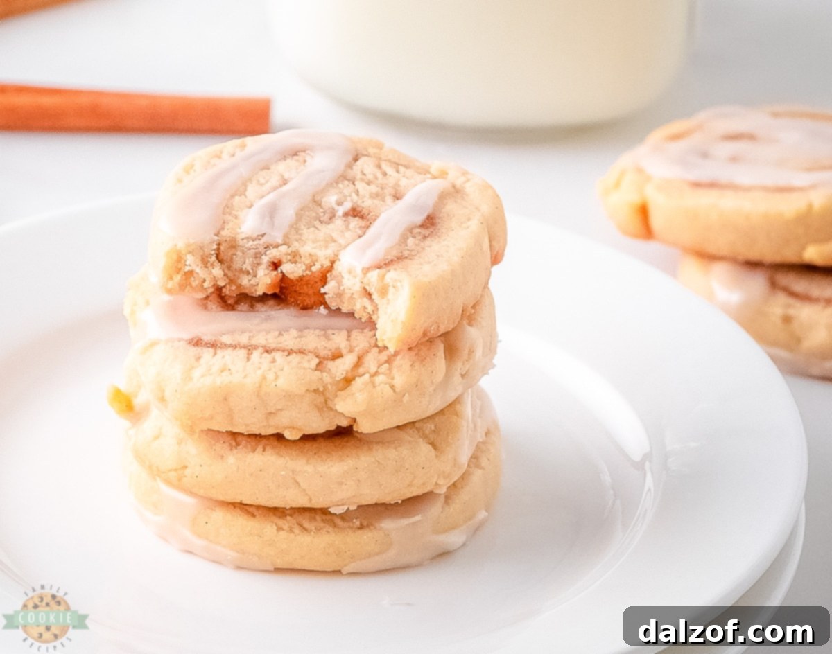 A tray of unbaked cinnamon roll cookie slices, neatly arranged on parchment paper, ready for the oven.