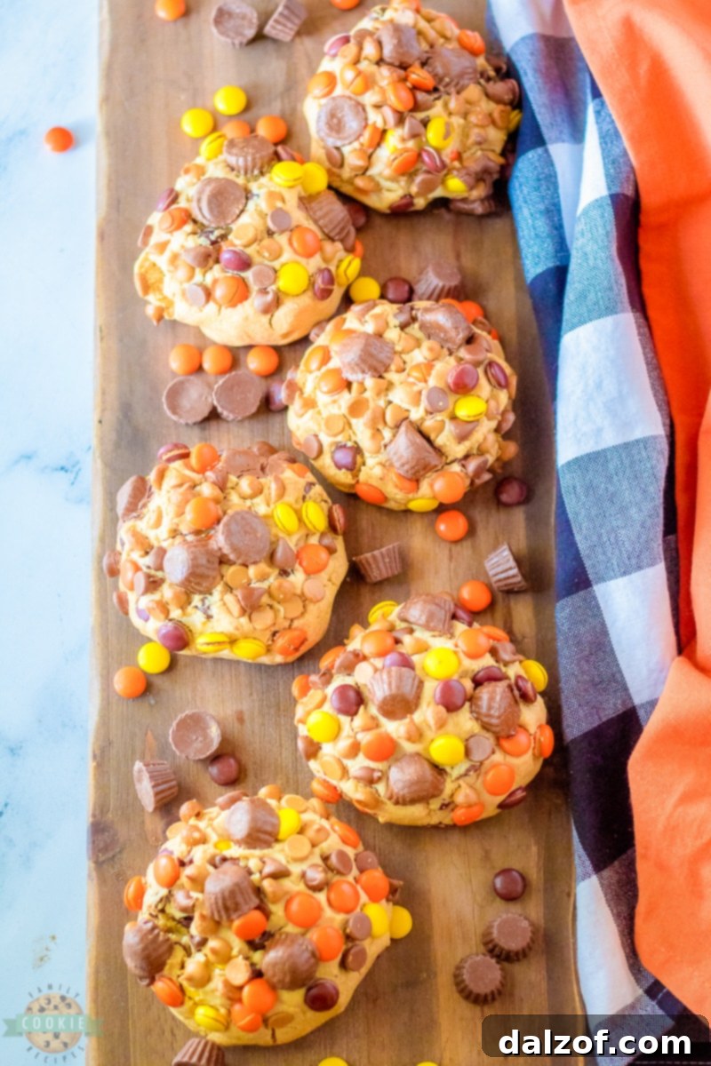 Six large balls of cookie dough, each pressed with additional Reese's candies, chilling on a baking sheet.