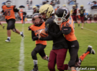 Two football players in action, one in orange jersey tackling another