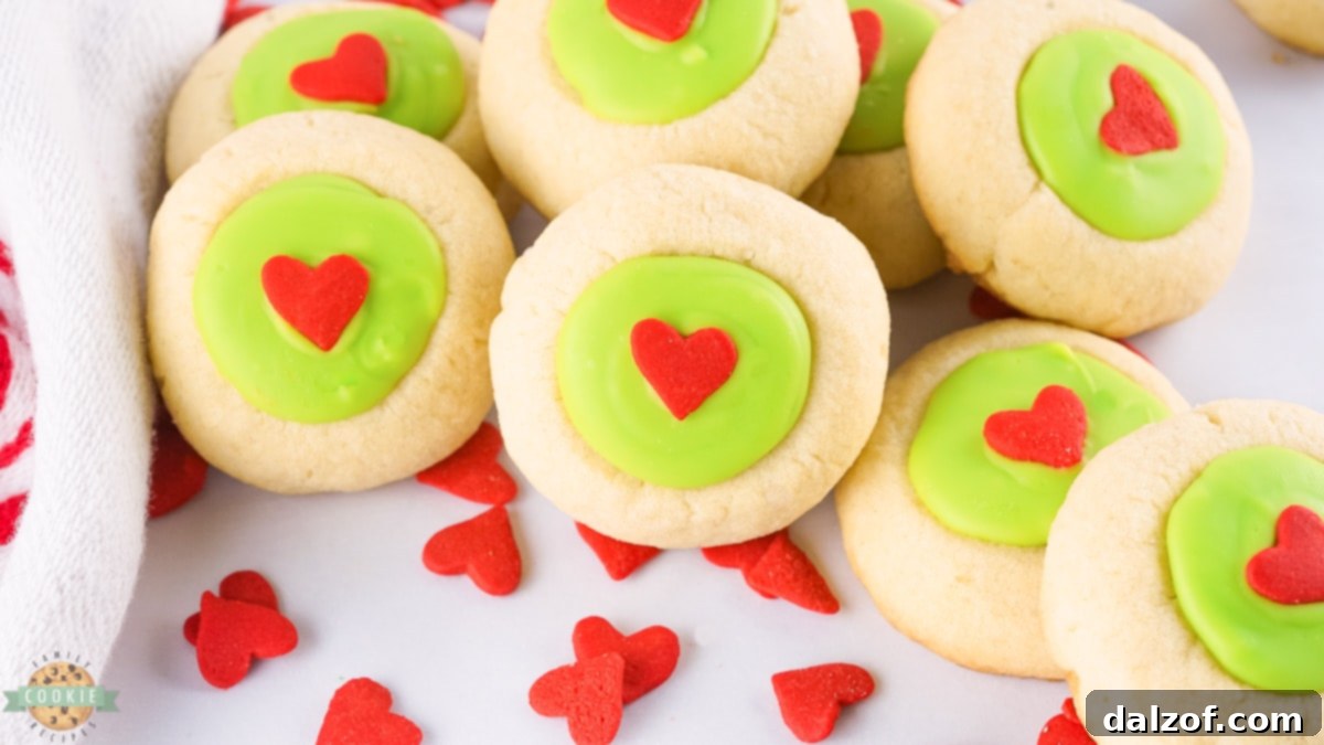 Festive Grinch Thumbprint Cookies with bright green centers and red hearts, perfect for Christmas.