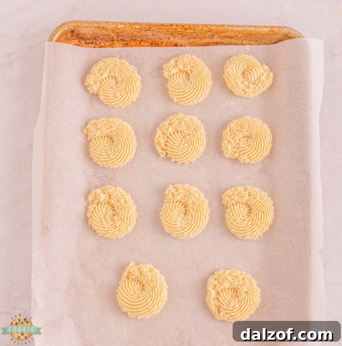 Golden Delights: Butter Cookie Recipes 6 Dough being piped onto a parchment-lined baking sheet, showing the technique for creating perfect butter cookie shapes.