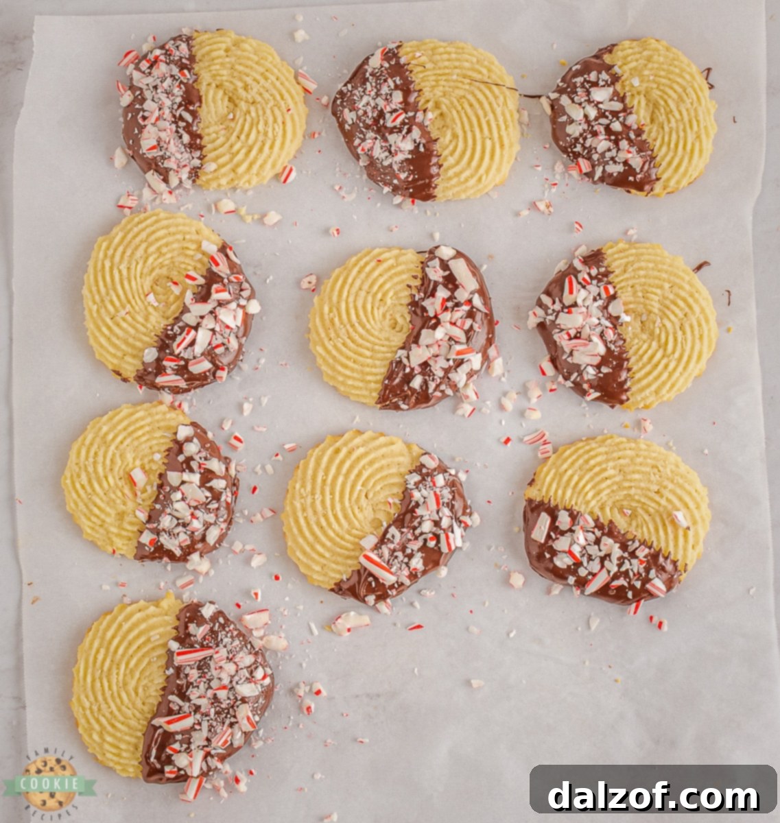 Piping peppermint butter cookie dough onto a parchment-lined baking sheet in elegant swirl patterns