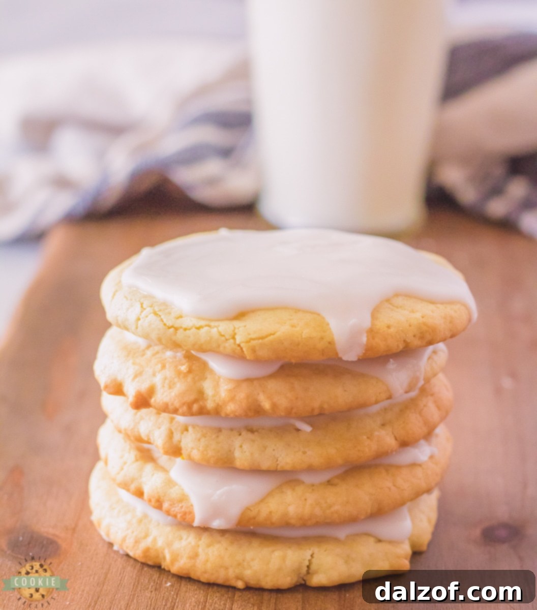 A stack of perfectly baked crispy sugar cookies, some with a hint of glaze.
