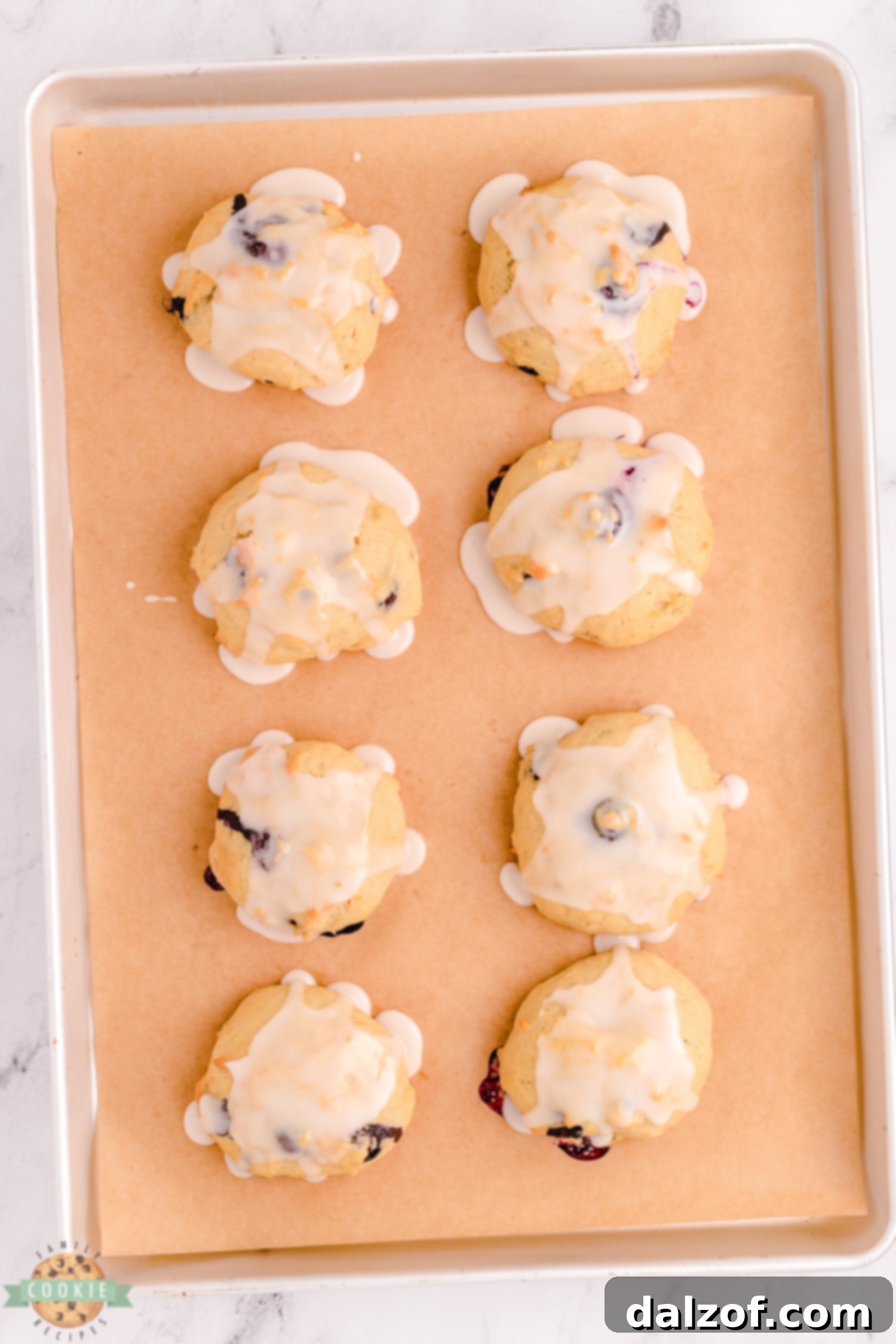 freshly baked and iced blueberry banana cookies on a baking sheet